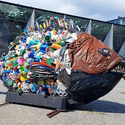 A large sculpture of a fish made out of plastic items