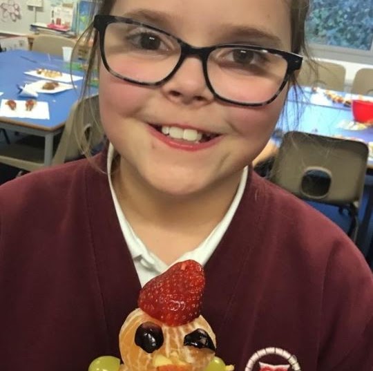 A girl showing a model made from fruit