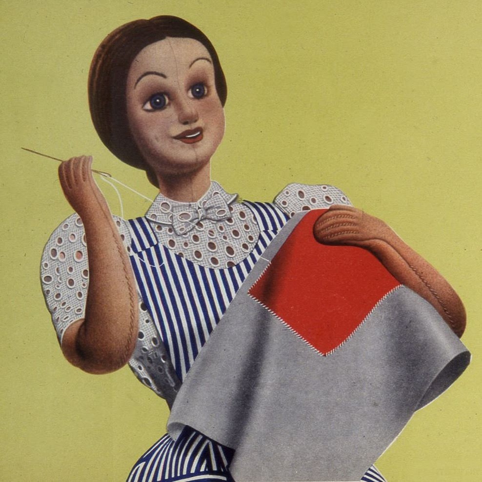A doll sewing a coloured patch onto fabric