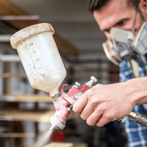 A man spray painting with a mask on