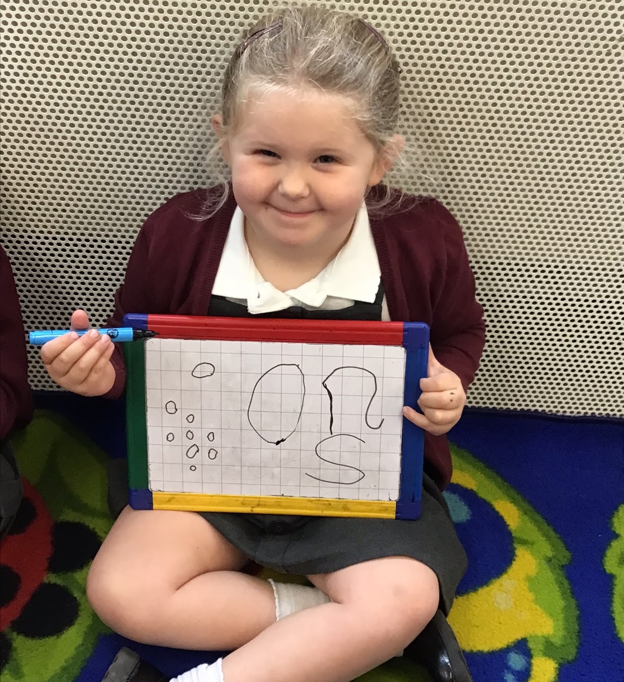 A smiling girl showing her writing on a board