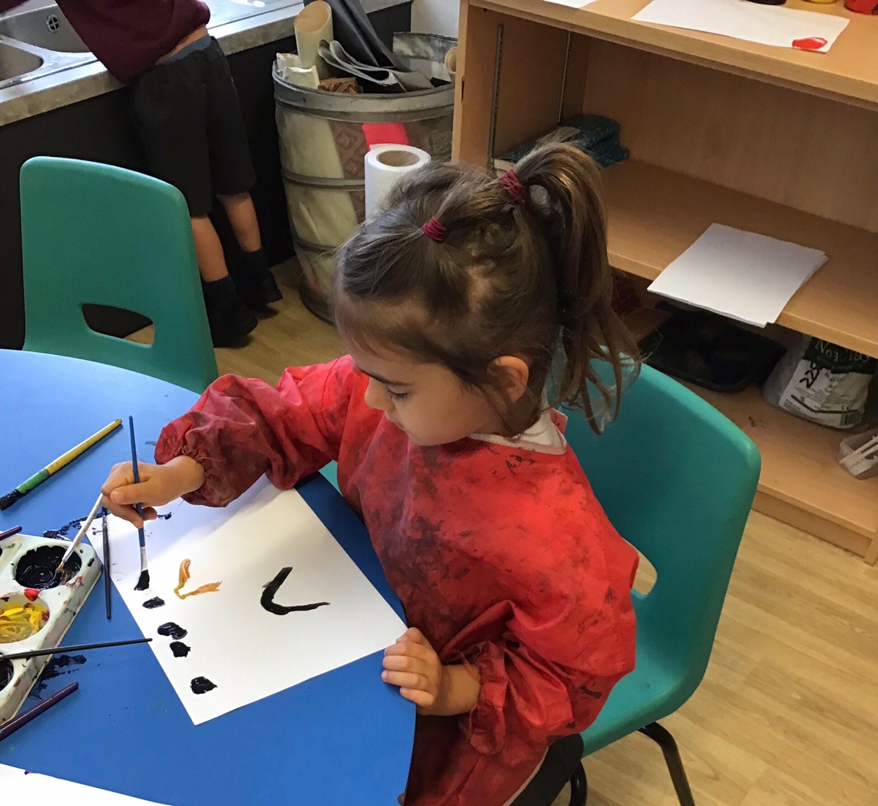 A girl sat at a table painting a picture