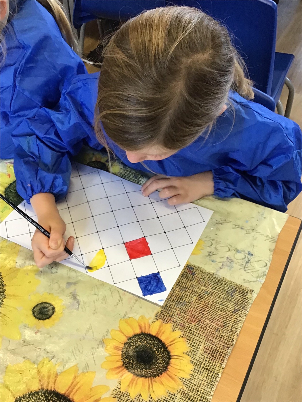 A girl painting coloured squares on paper