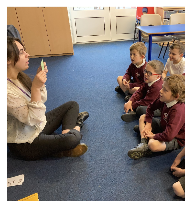 A teacher working with a group of children on phonics sounds