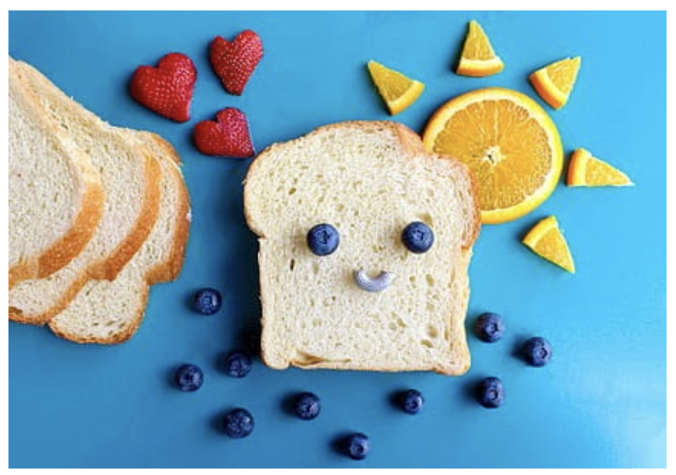 A piece of bread with a smiley face formed out of fruit